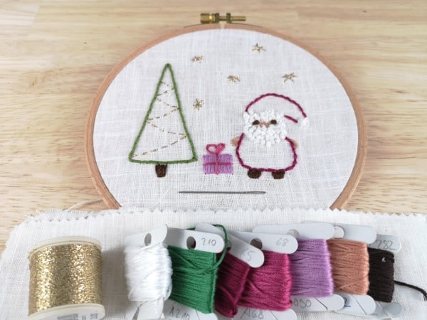 Stickbild mit Weihnachtsmann, Weihnachtsbaum, Geschenk und Stickmaterial